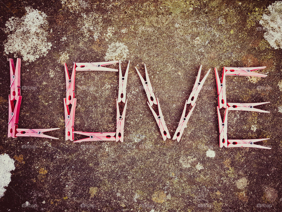 Brilliant Pink clothes pegs spelling out the word LOVE on a stone background.