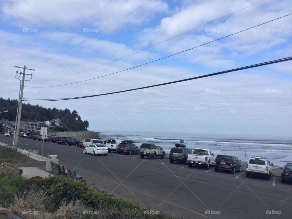 Cars Going Down the Street by the Beach in Seaside, Oregon on a Sunny Day withe the inlet in the distance 