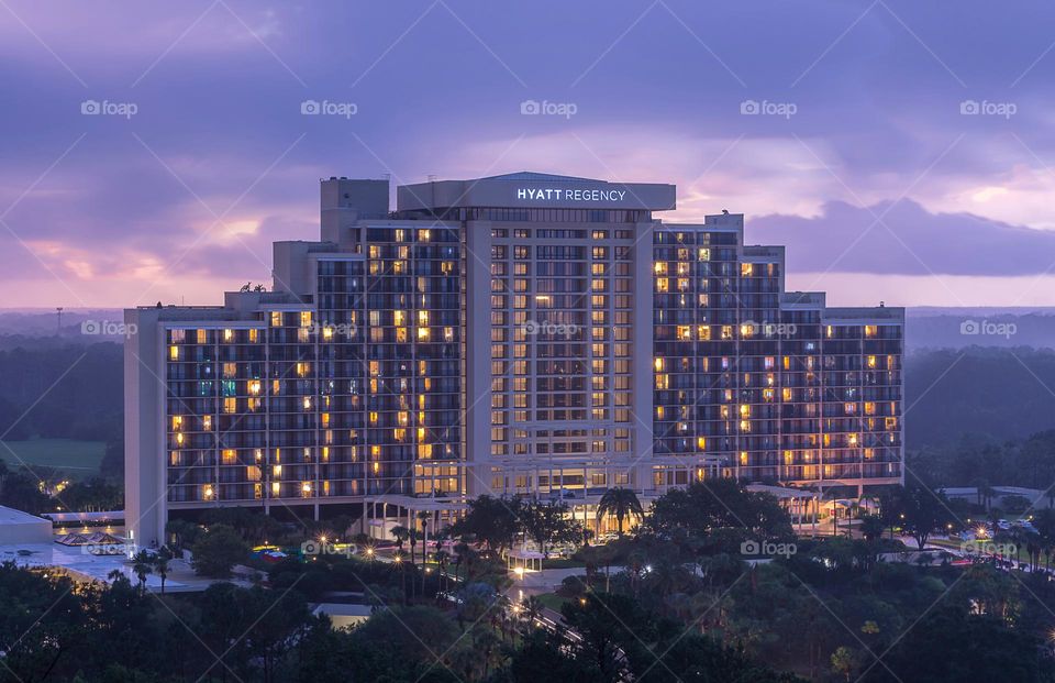 lights of the Hyatt Regency hotel building in the Disney Buena Vista area near Orlando Florida, USA sparkle in front of a beautiful purple sky on a stormy day