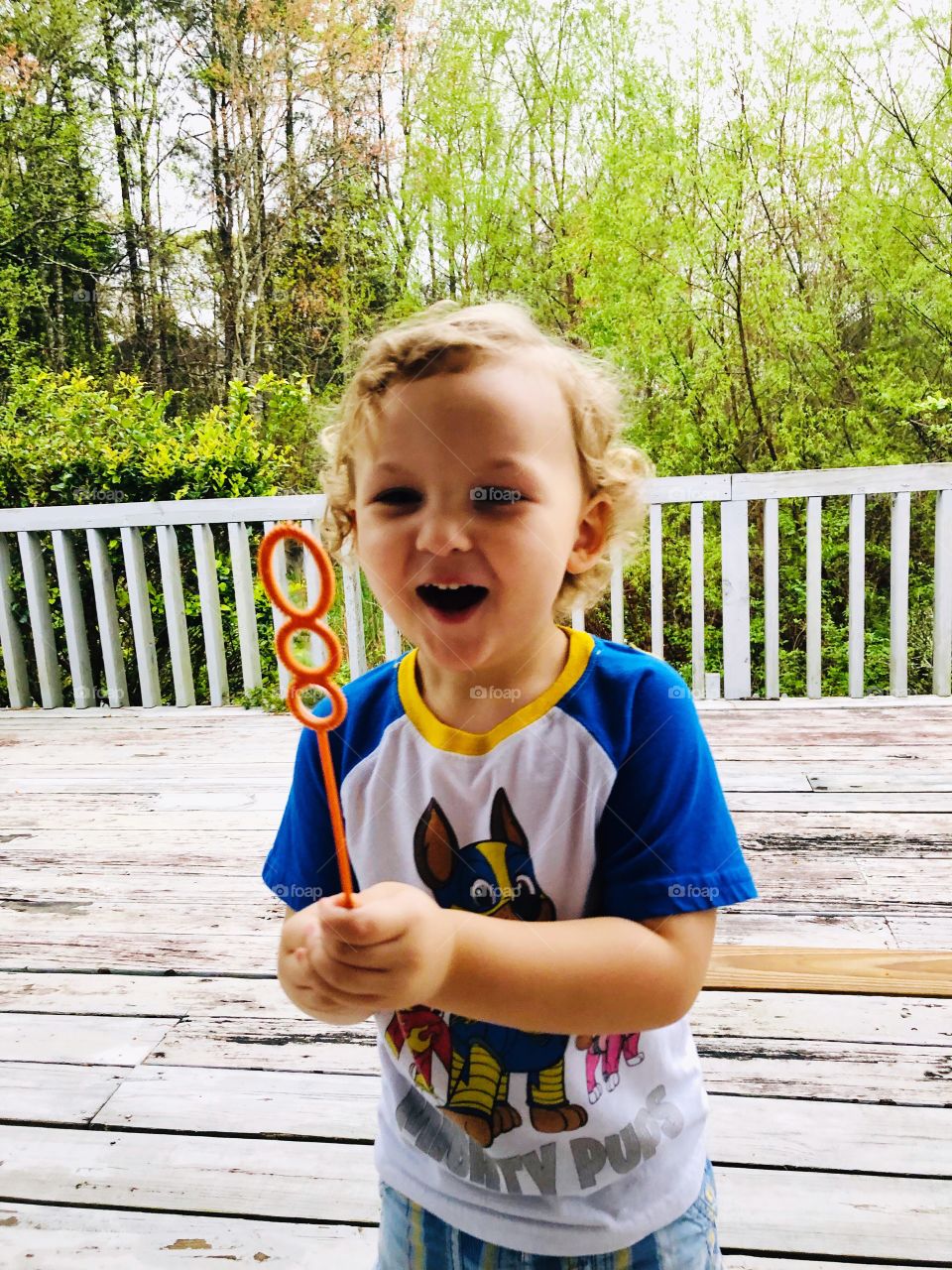 Toddler boy laughing blowing bubbles outside 