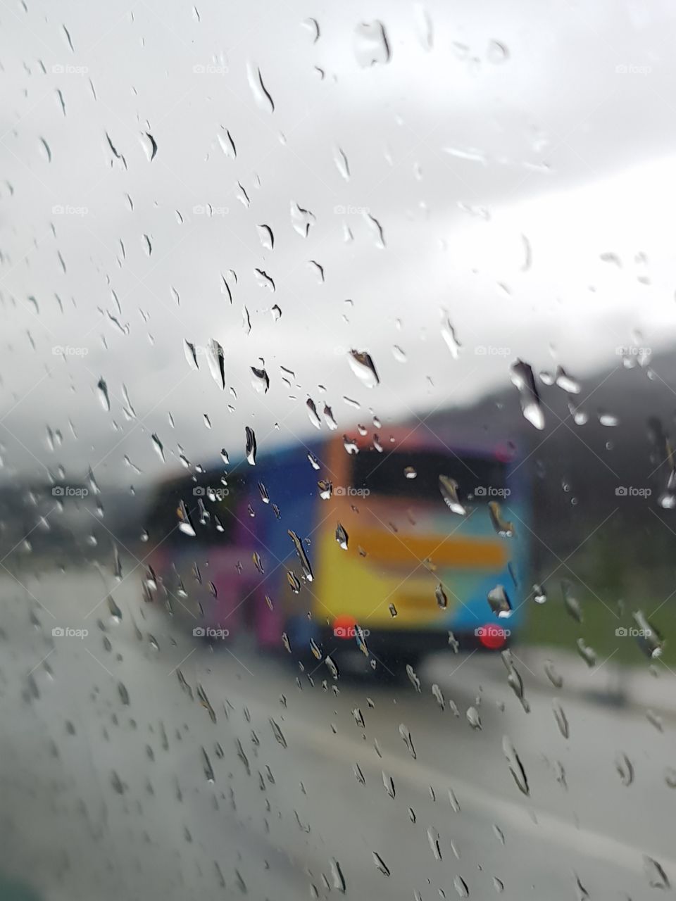 Colorful bus through the sad rainy glass
