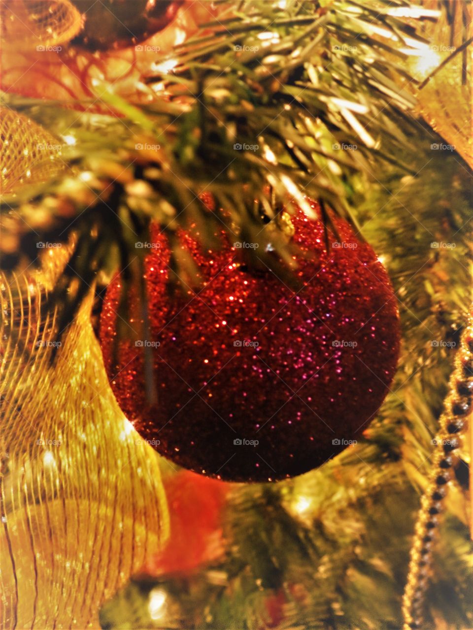 Glittery Christmas bulb on a tree.