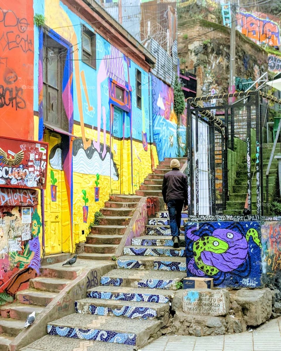 A man walks up some stairs surrounded by street art