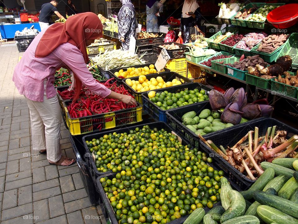 a lady buying fruits and vegetables at a market