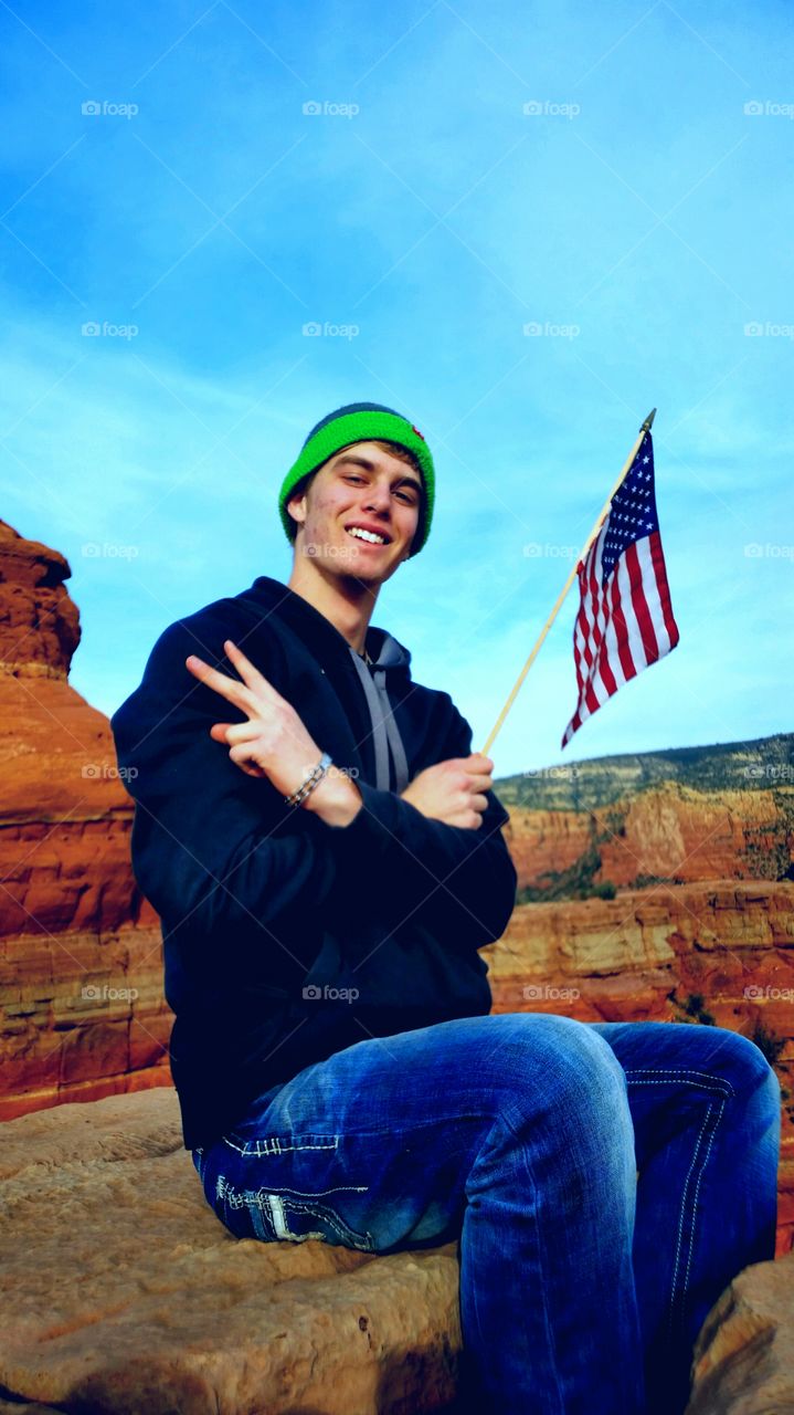 Young man holding american flag with victory sign at Arizona