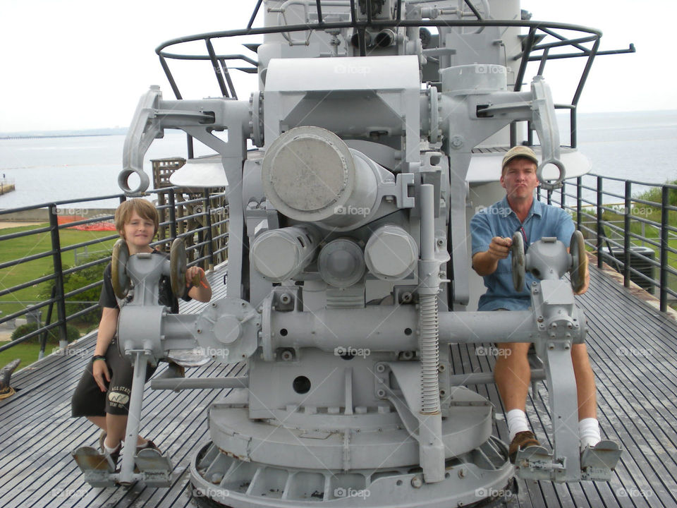 Man and boy looking through gunners on USS Alabama battleship Memorial Park Alabama