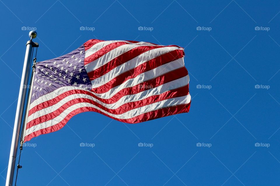 American flag on pole flying in the breeze against vivid clear blue sky