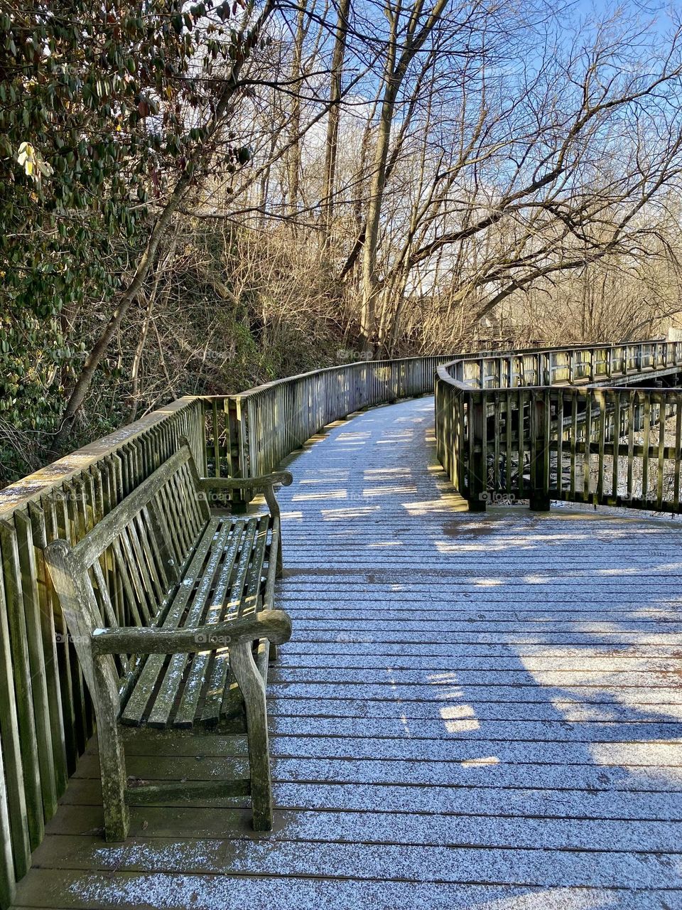 Snow and shadows on a boardwalk around a quarry lake at a local park 