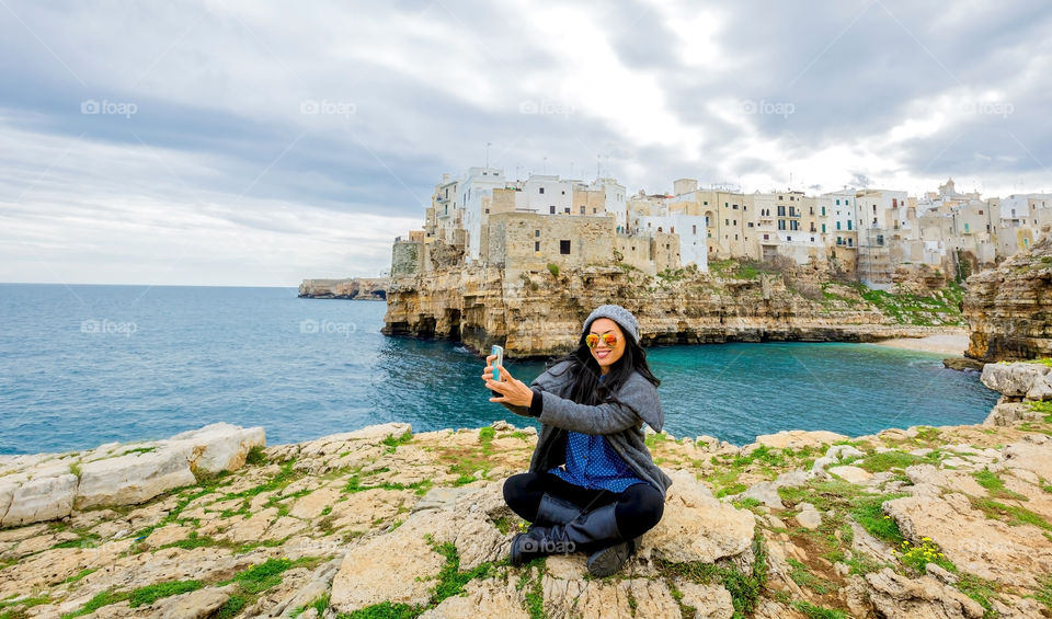 Tourist taking selfie with old town of Polignano a mare