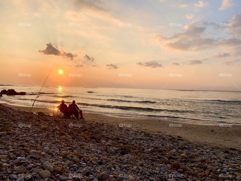 Fishermen sitting watching sunset 