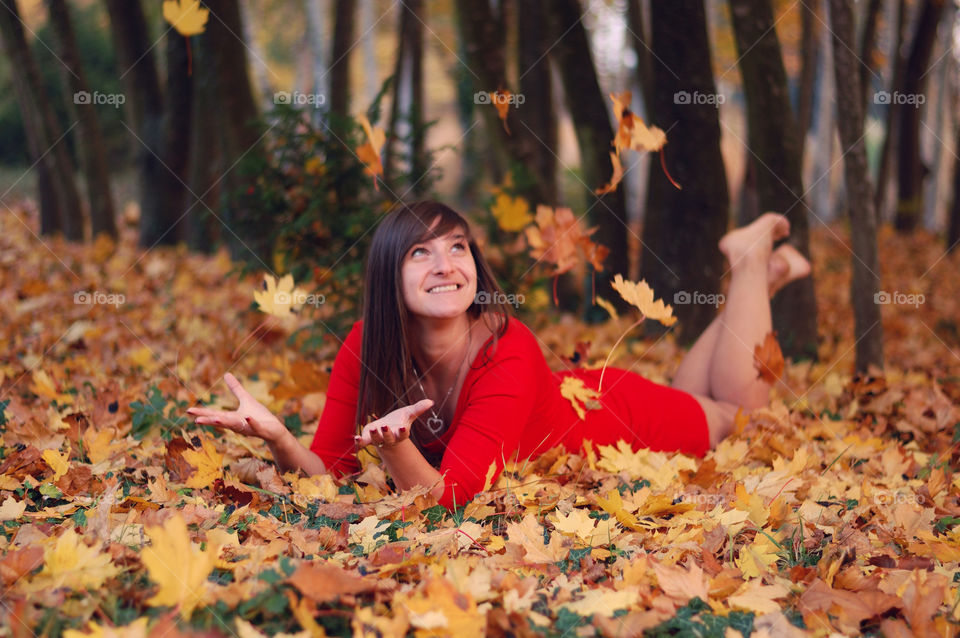 Woman lying on autumn leaves in forest