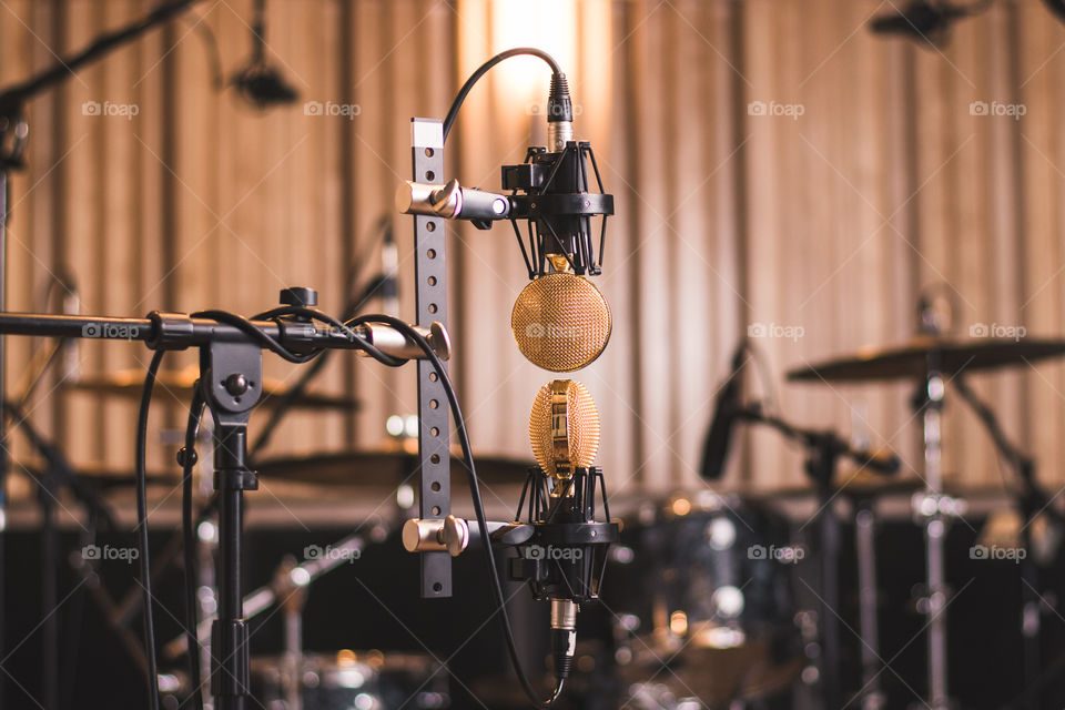 Recording arts studio for musicians has a golden microphone for singers and a drum kit in the background 