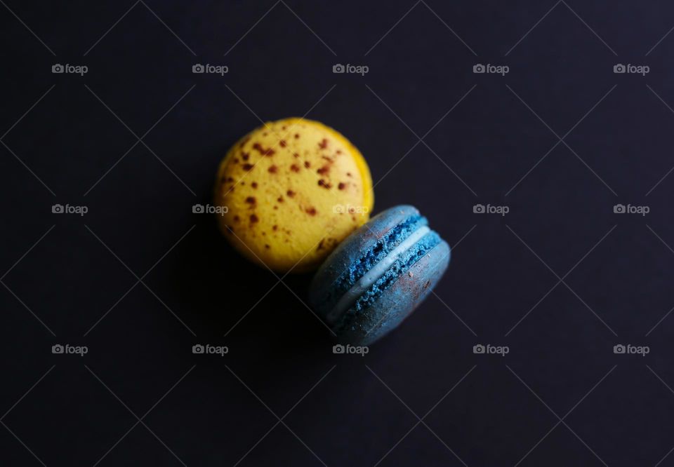 delicious macaroons, yellow-blue in color with various flavors, on a black background