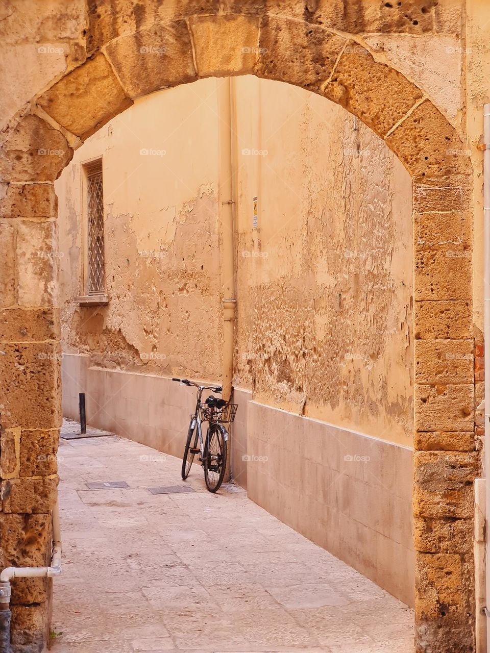 solitary bicycle leaning against the wall under an arch in the historic center of Bari in Italy
