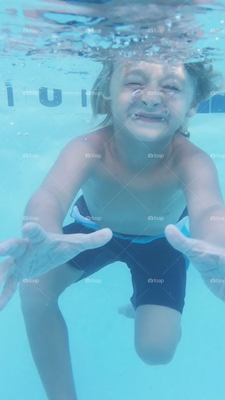 Cute boy swimming underwater in pool