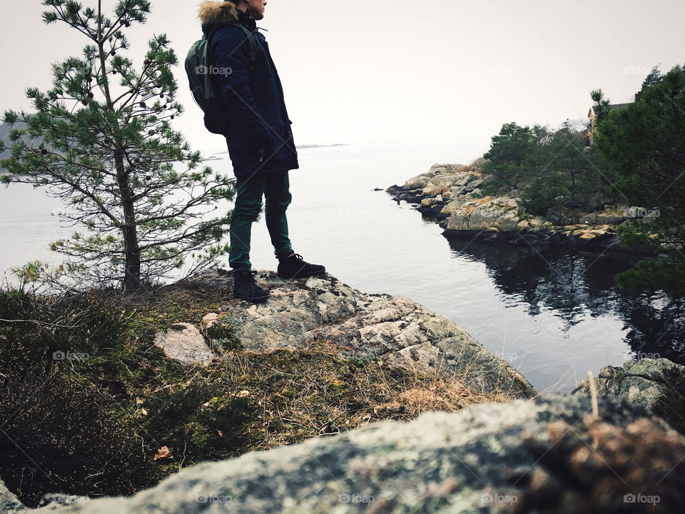 Side view of a man standing on rock near the lake