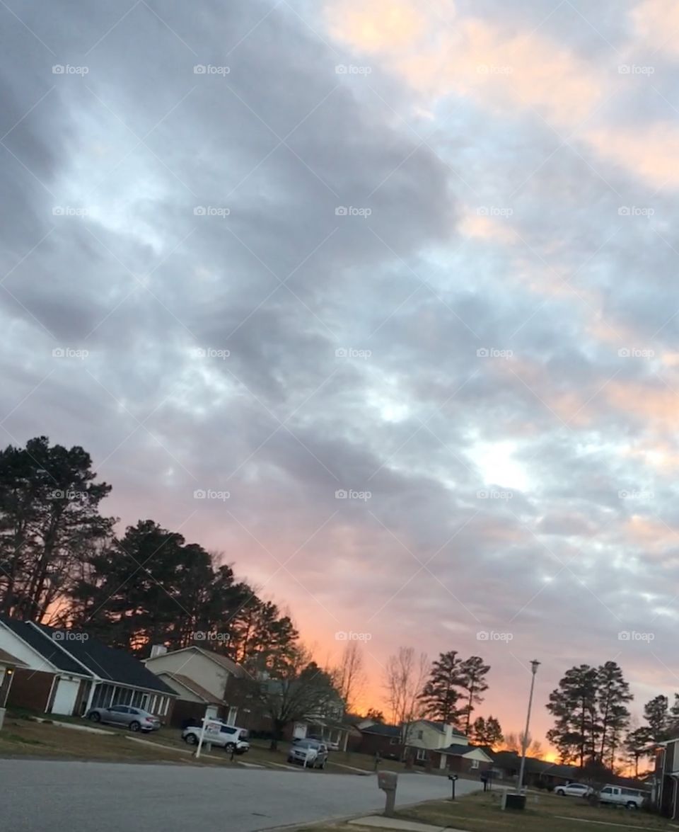 Beautiful setting sun behind the clouds of a subdivision 
