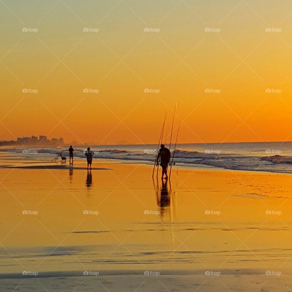Silhouette of people at beach during sunrise