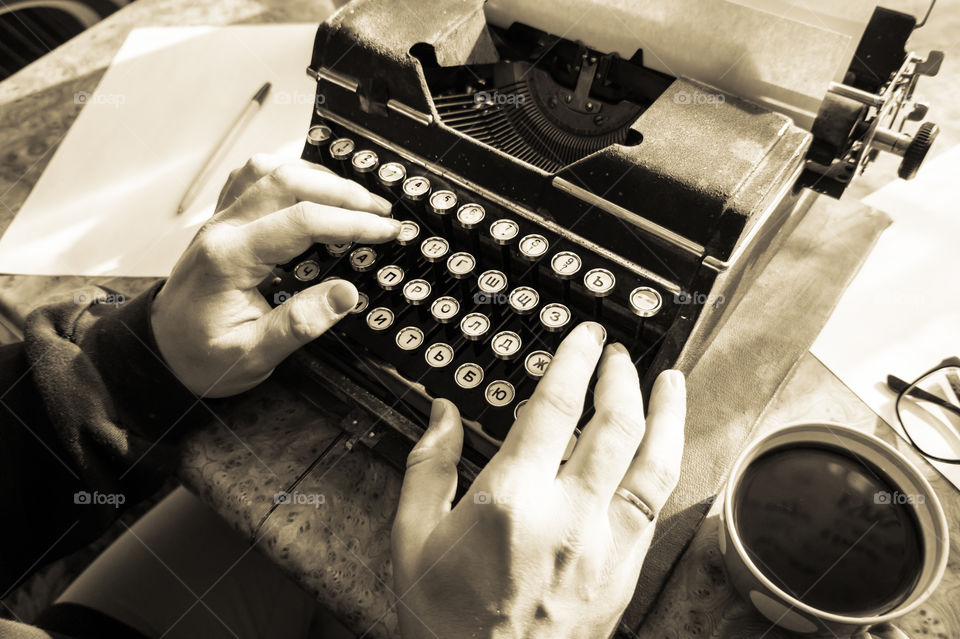 A young writer is writing a new book on an old typewriter.