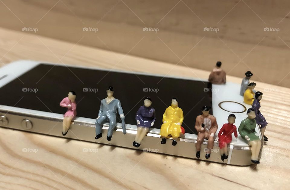 Miniature model people sitting on an iPhone 