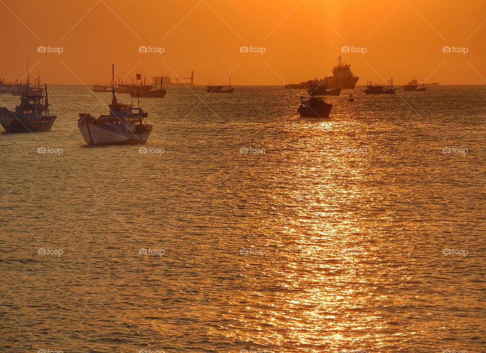 Boats in Orange sunset. . This is VingTtau, Vietnam. Picture taken from public embankment. It was a beautiful warm evening. 