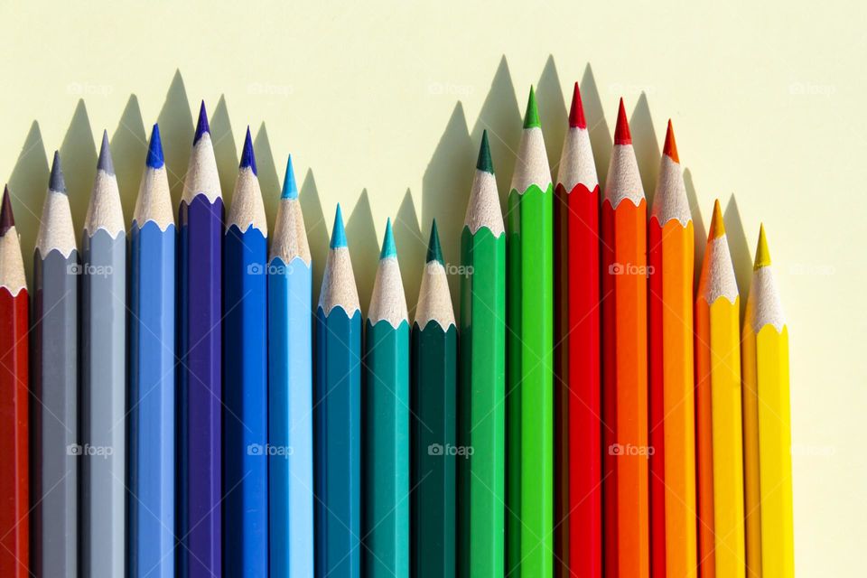 A large number of sharpened colored pencils with falling shadow from natural light on a bright sunny day.