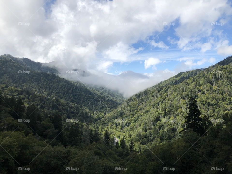 Huge Puffy Clouds hanging in Sky above Mountain Range 