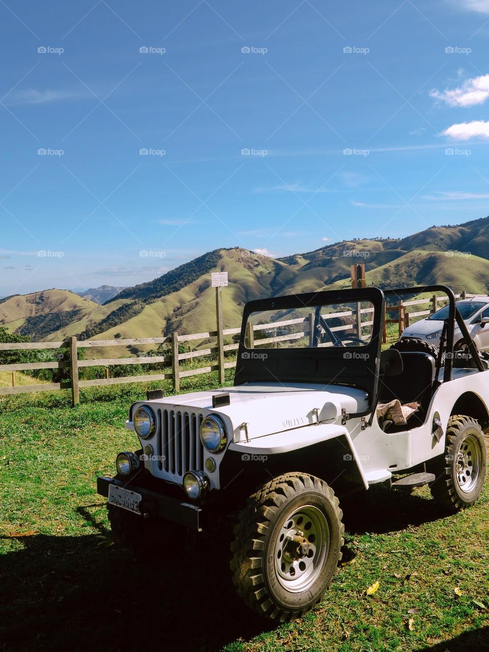 White Jeep, on a beautiful mountain landscape. A beautiful blue sky and green grasslands add color to the composition.
