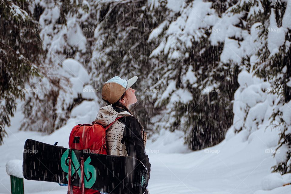 woman being mesmerized by the snow while wearing her snowboard