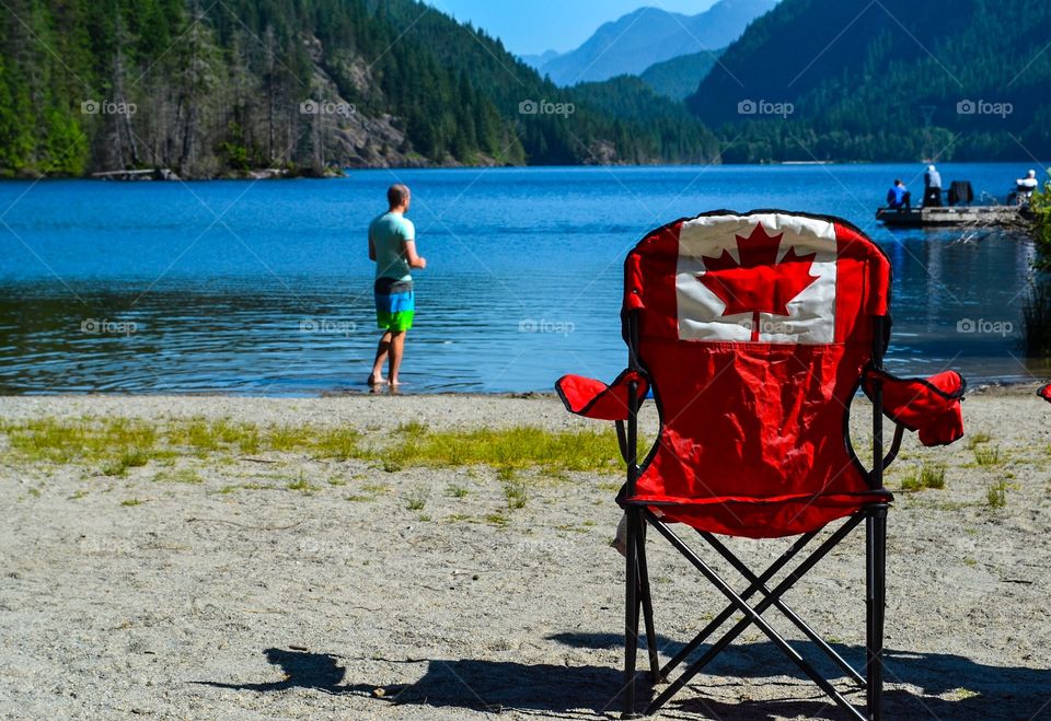 Canada, Canadian flag maple leaf bright red chair at Buntzen lake in beautiful British Columbia, Canada's west coast 