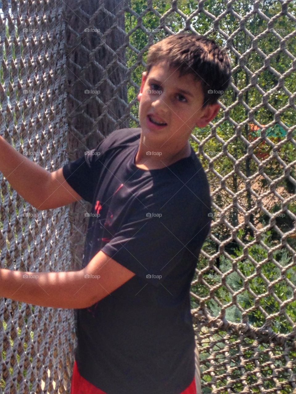 Going up. Boy climbing a rope wall