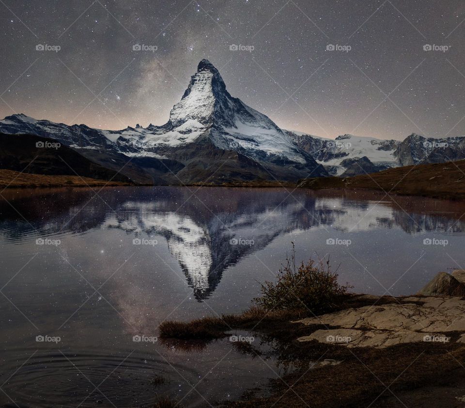 Matterhorn reflected in lake stellisee with milky way above.
