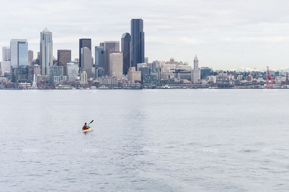 Kayaker in Seattle. A lone kayaker paddles toward the Seattle skyline on a calm spring day.