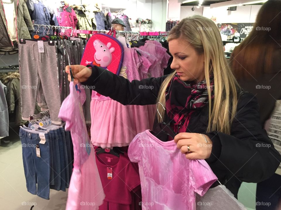 Woman shopping children clothes in local store (Primark) in London.