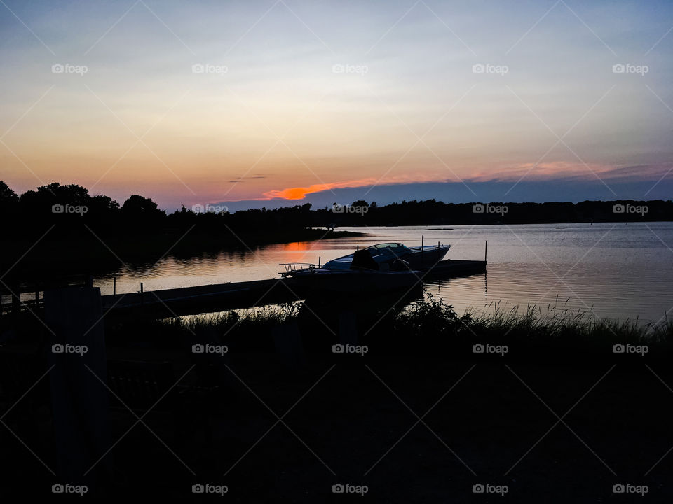 Sunset over the river.  The boats at the dock are silhouetted in the foreground.