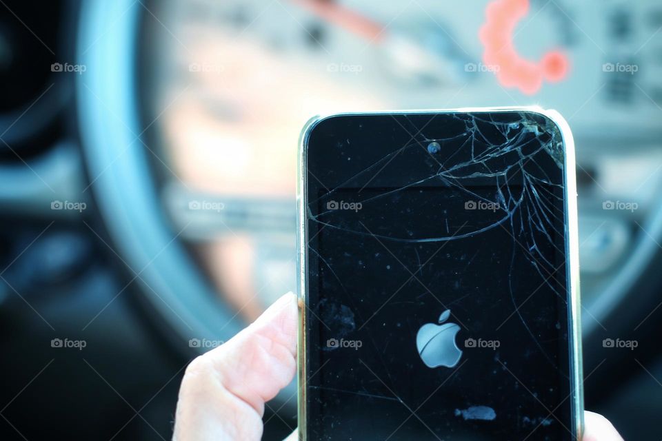 Apple iPod with broken display is held by one hand in the car