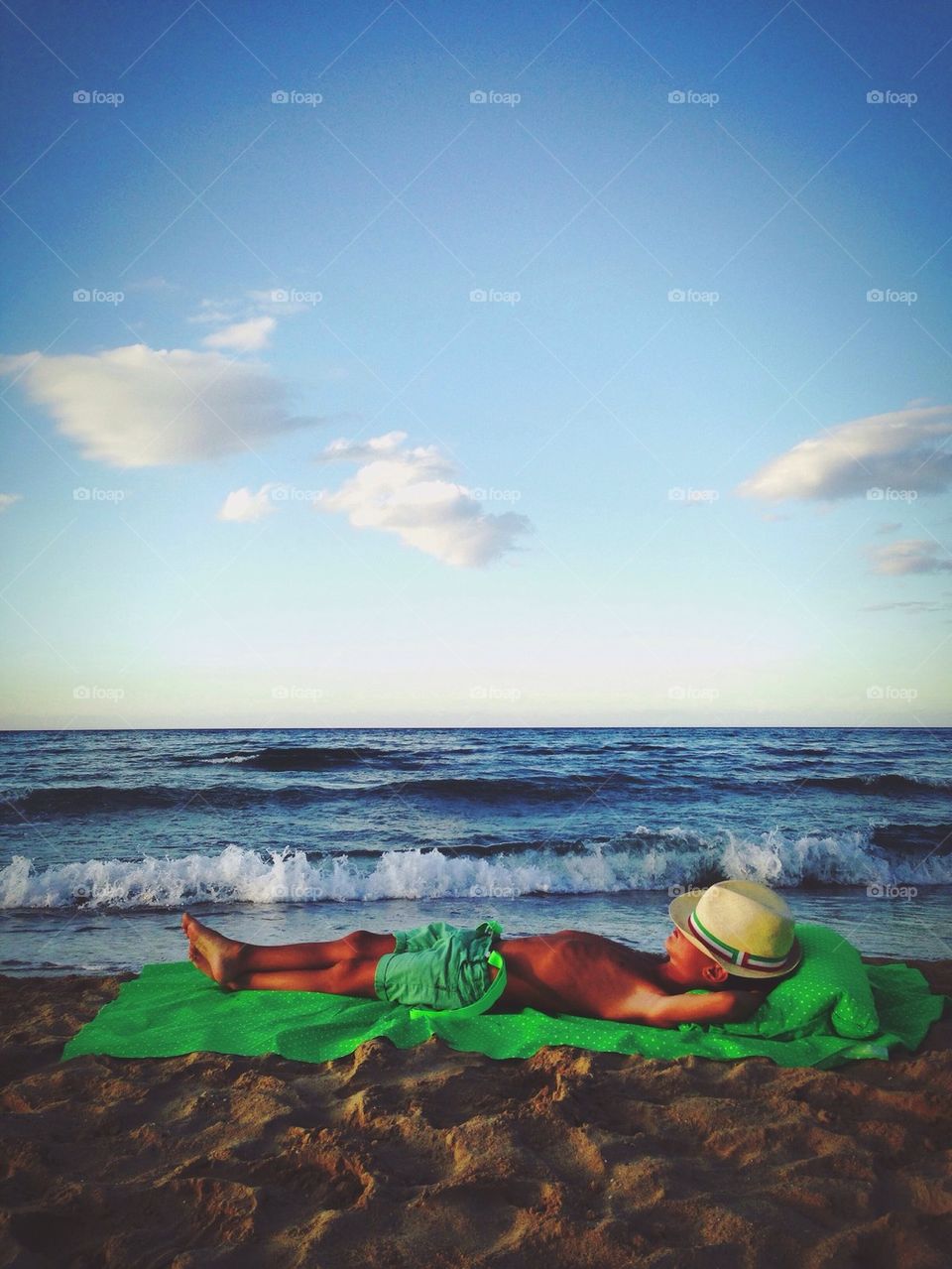 Boy relaxing on tranquil beach wearing hat