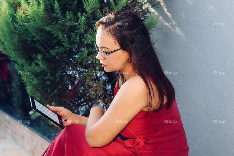 woman in red dress reading a book on Kindle