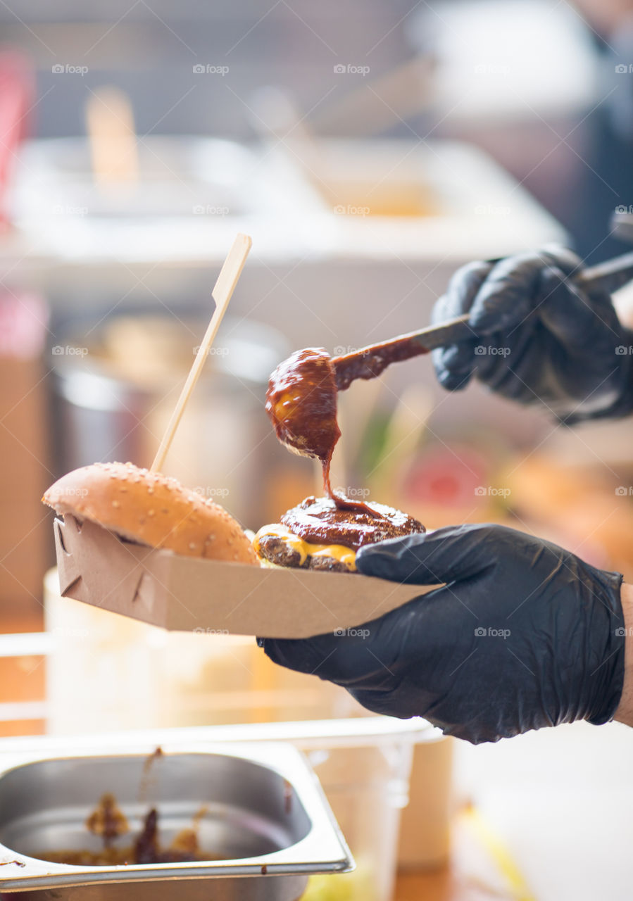 Chef's hands in gloves preparing burger on a fast food restaurant