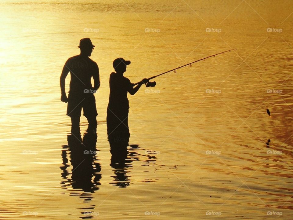 Father and son fishing at sunset silhouette 