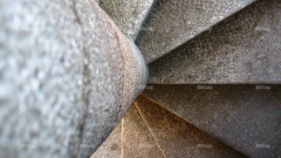 Abstract view of a stone spiral staircase, seen from above, spinning around the central column.