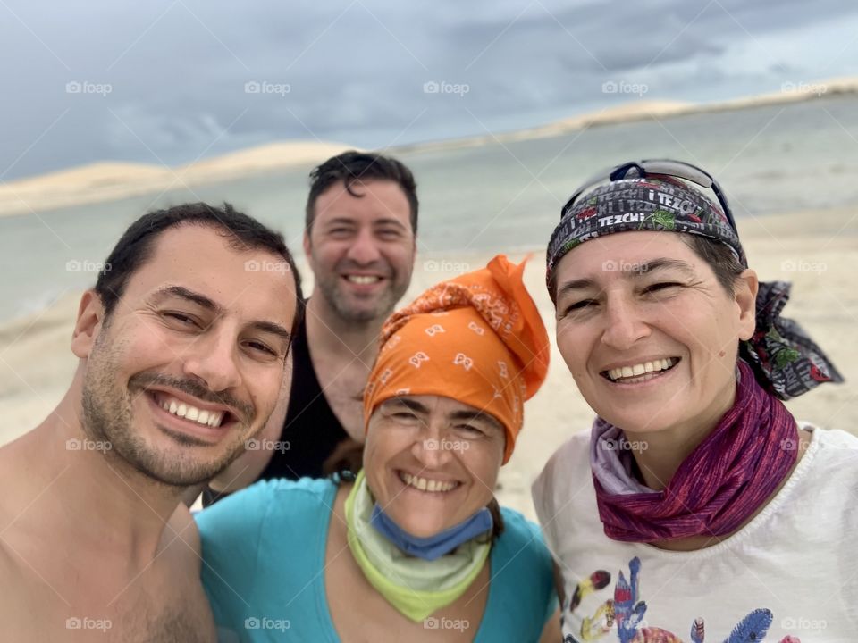 Four friends against rain lake and dunes 