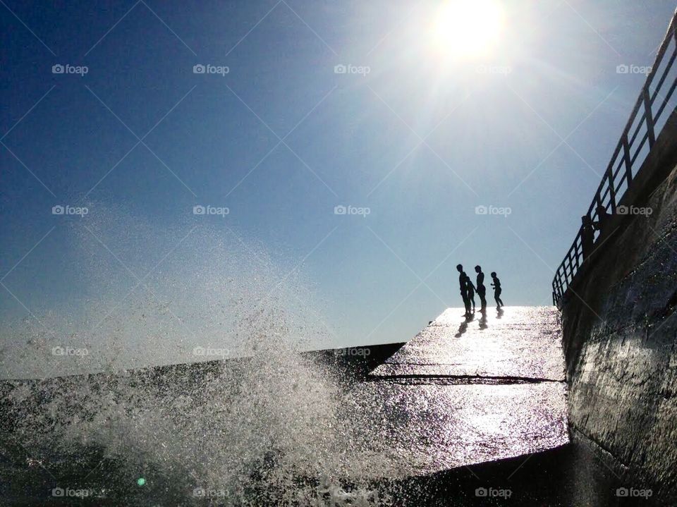 Silhouettes standing on the edge above the sea.