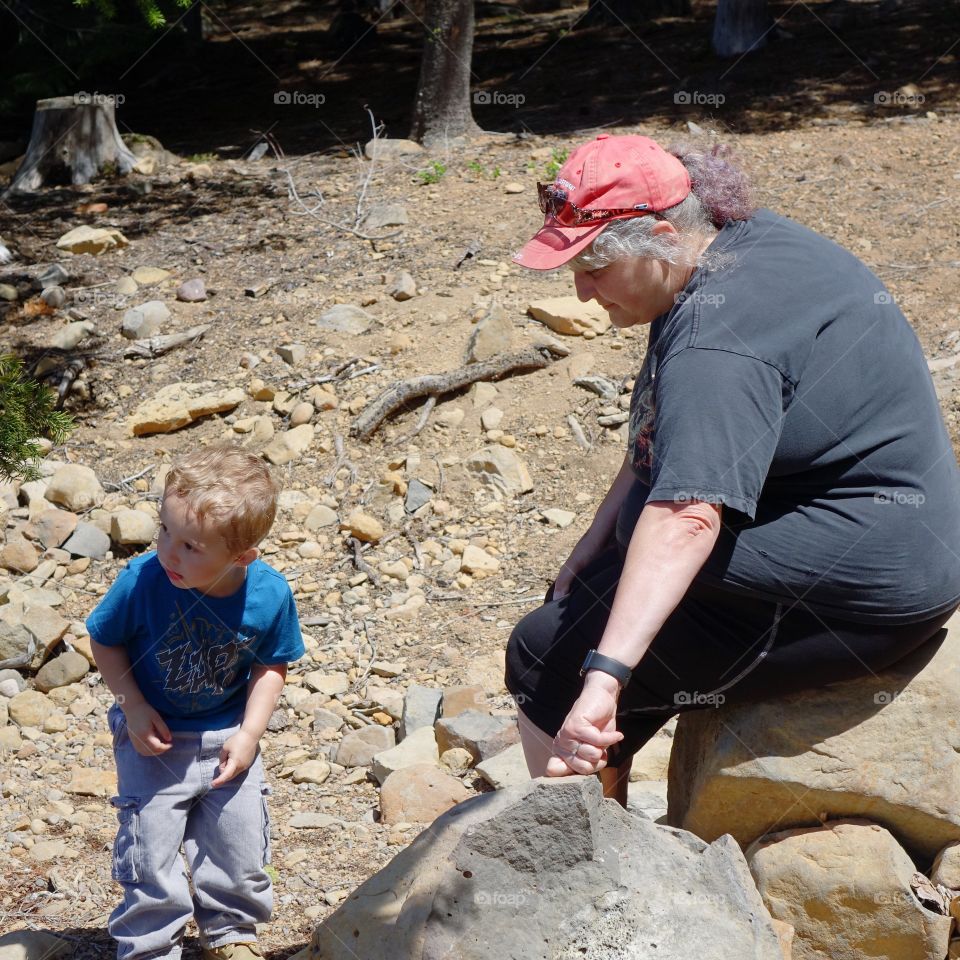 A grandma and her young grandson explore the shores of a high mountain lake together in Central Oregon on a sunny summer day. 