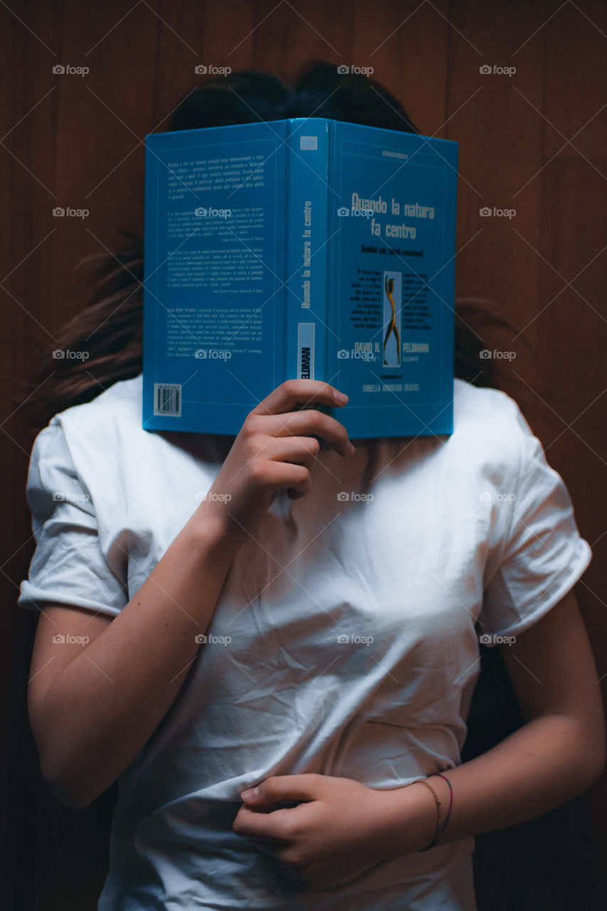 Girl lying on the floor at home with a book in her arms