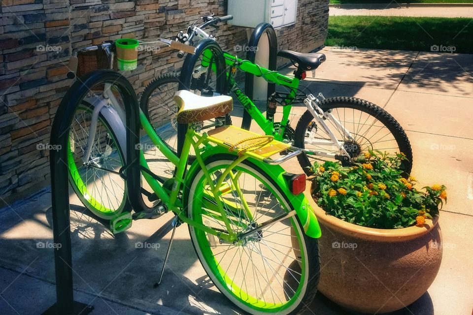 Two bright green bikes parked in an urban setting riding around town It's summertime