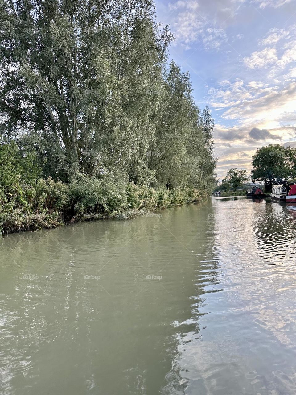 Cool sky clouds sun along Oxford canal narrowboat cruise late summer evening trees water clear weather countryside looking for a place to moor for the night