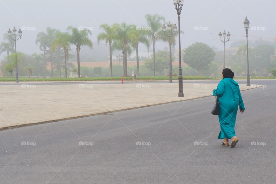 A local woman walking on a foggy morning on the grounds of the Royal Palace in Rabat, Morocco.