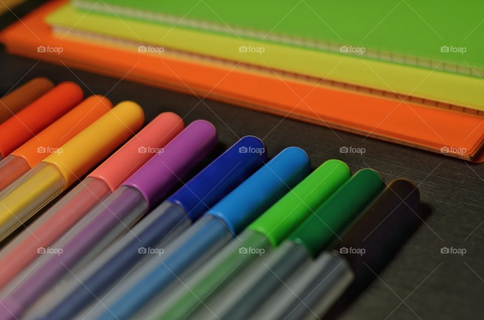 Colorful pencils and notebooks on the black background.