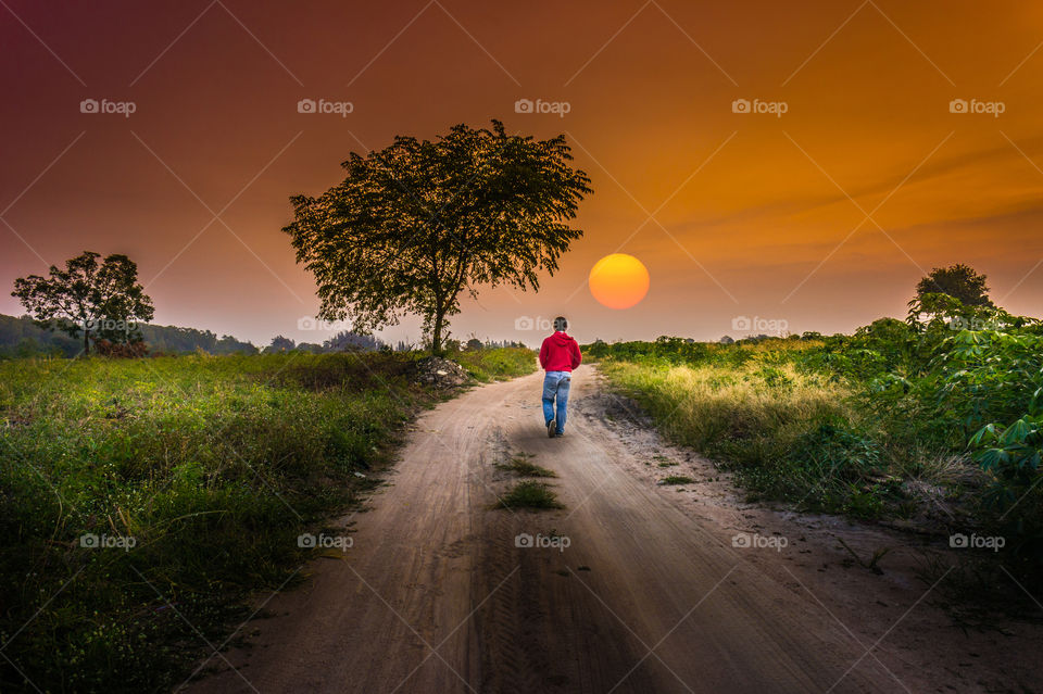 Man walking alone at country way with sunset.